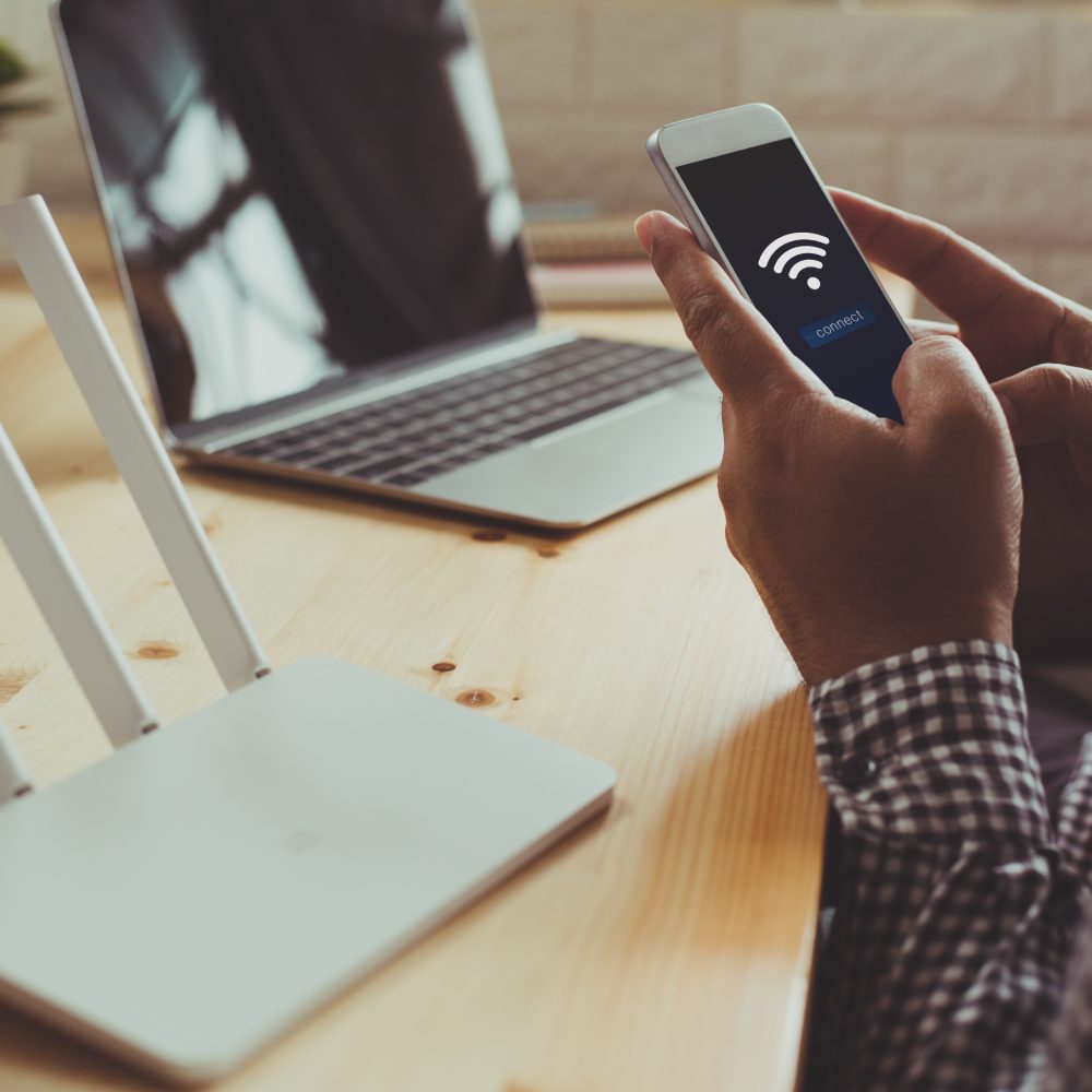 closeup of a wifi router and a man using smartphone on living ro