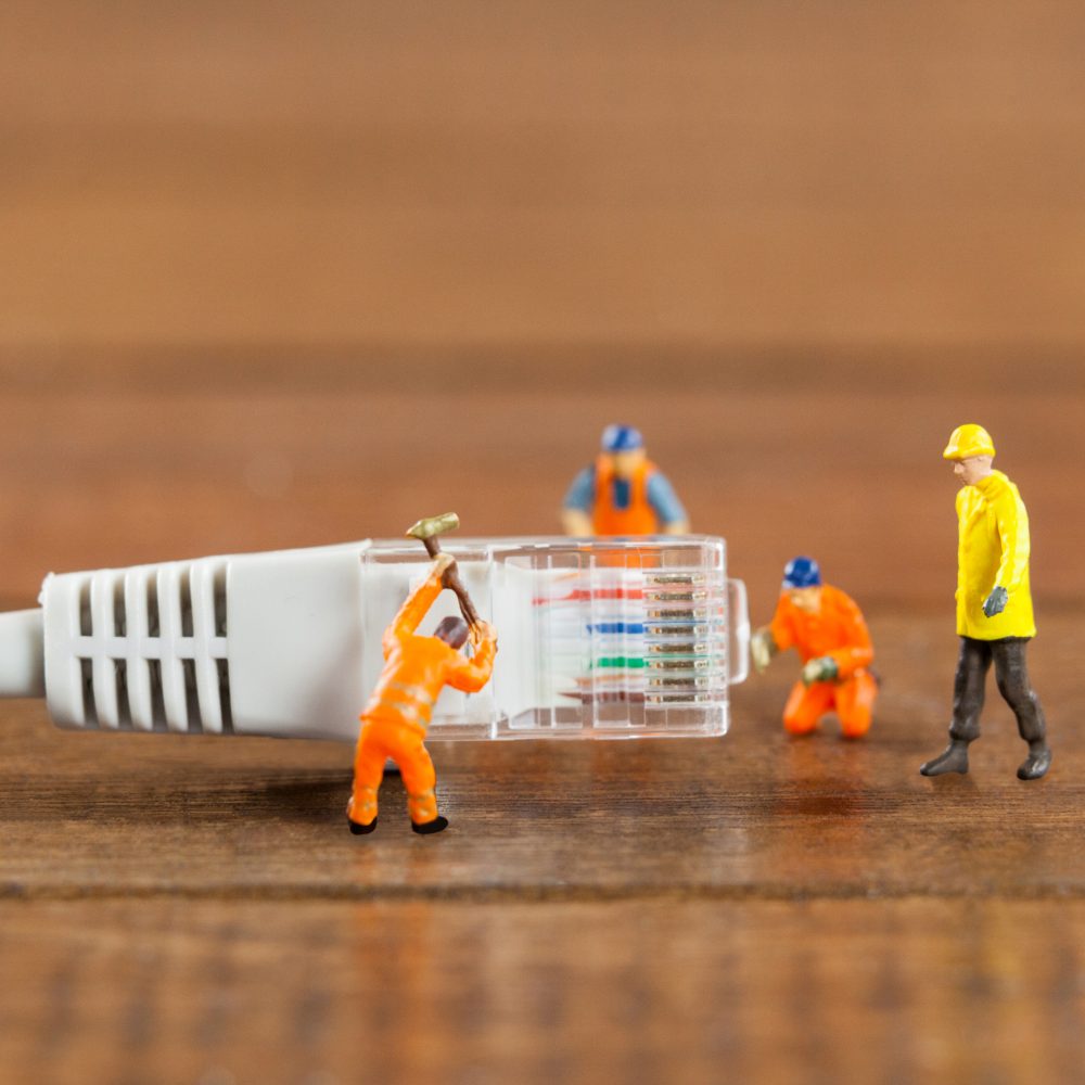 Miniature engineer and workers working with lan cable